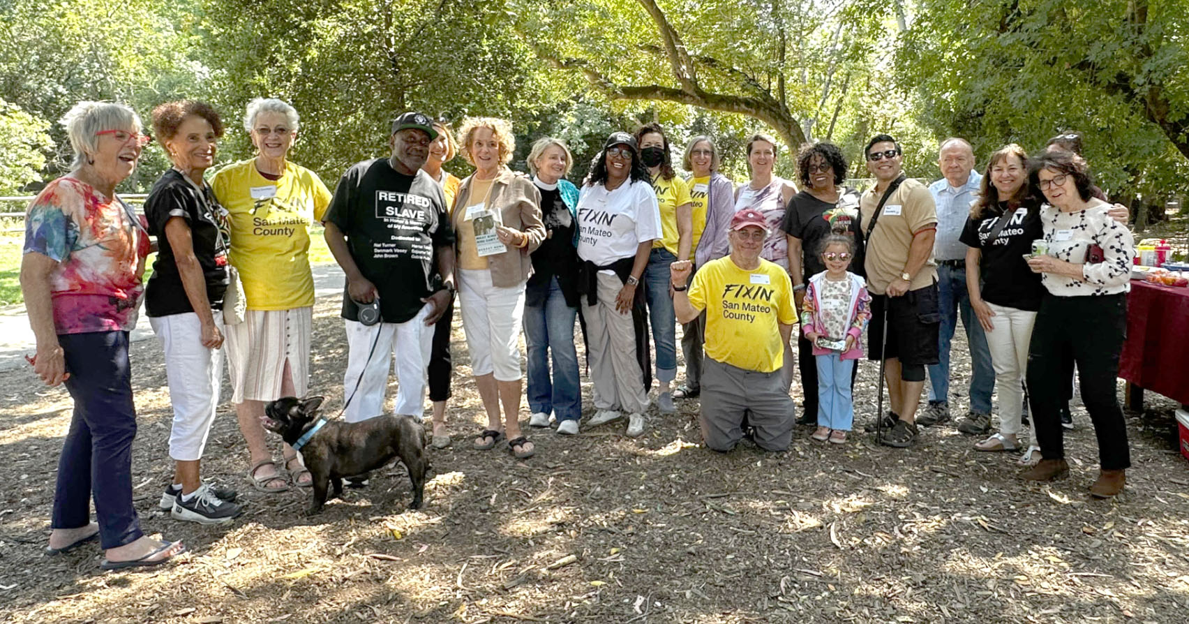 SummerInThePark2025-group Nineteen of the attendees at our event gathered under the trees in Twin Pines Park. In the foreground, one dark brindle French bulldog.